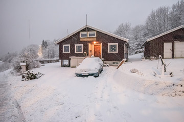 Snowy driveway of a brown house in winter.