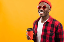 Portrait Of A Black African Man Dressed Stylishly Holding A Drink Glass On A Yellow Background With Copy Space