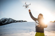 © lightpoet - Young man controlling his drone in snowy outdoors. Drone operator holding a transmitter and landing with a drone.