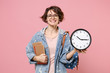 Smiling young woman student in denim clothes, eyeglasses, backpack posing isolated on pastel pink background. Education in high school university college concept. Mock up copy space. Hold books clock.
