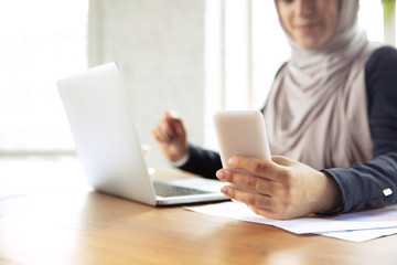 Wall Mural - Using gadgets. Portrait of a beautiful arabian businesswoman wearing hijab while working at openspace or office. Concept of occupation, freedom in business area, leadership, success, modern solution.