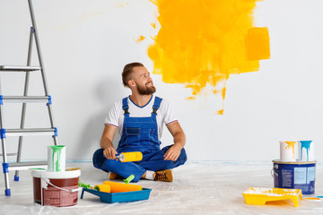 Wall Mural - Repair in apartment. Happy man worker paints wall .