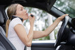 © auremar - woman applying makeup while driving her car