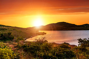 A bright orange crimson sunset in the valley of Wichita Mountains Wildlife Refuge near Lawton, Oklahoma, USA.