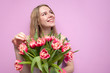© Богдан Маліцький - young beautiful girl with a bouquet of flowers on a colored pink background, a woman holds tulips and smiles