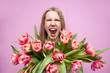 © Богдан Маліцький - emotional girl holds a bouquet of flowers on a pink background, a happy woman with tulips screams for joy