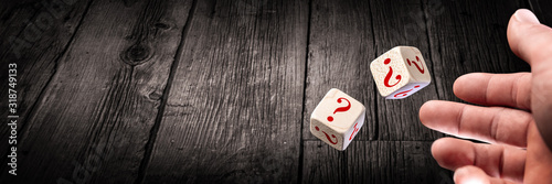 Fotomural Hand Throwing Two Dice With Red Question Marks Onto Wooden Table