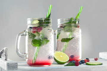 Wall Mural - Homemade cold summer cocktail with mineral water, mint, lime, berry juice and fresh berries