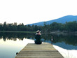 © bennnn - Rear view on young woman sitting on wooden pier in the evening looking at calm lake