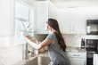 © MeganBetteridge - Women holding indoor plant in a white kitchen