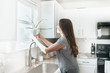 © MeganBetteridge - Women holding indoor plant in a white kitchen