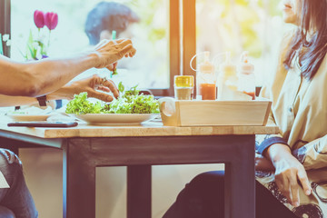 Happiness woman and friend talk and eat salads on the table in restaurant. Selective focus on lettuce.