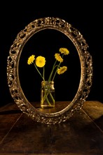 Vertical Shot Of Yellow Flowers In A Glass Jar Reflected On The Mirror