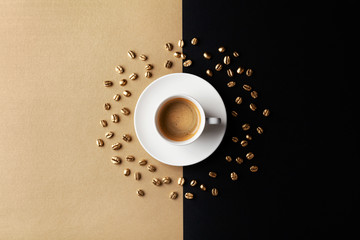 Cup of coffee and coffee beans on gold black background. Creative flat lay. Top view.