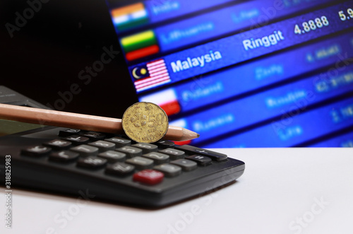 Fotomural Fifty cents coin of Malaysia and pencil on the calculator with digital board of currency exchange money background