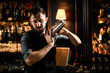 Bartender holding a steel shaker with a cocktail ready to shake it in the bar