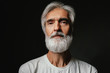 Studio portrait of frowning senior man with gray beard.