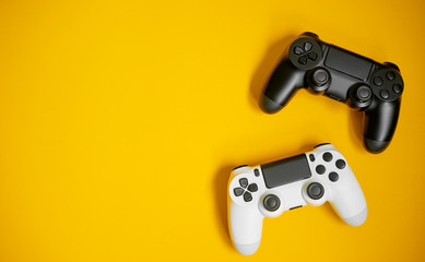 Wall Mural - Computer game competition. Gaming concept. White and black joysticks on yellow background.