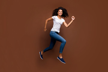 Poster - Full length profile photo of funny dark skin lady jumping high rushing mall black friday shopping addicted wear casual white t-shirt jeans isolated brown color background