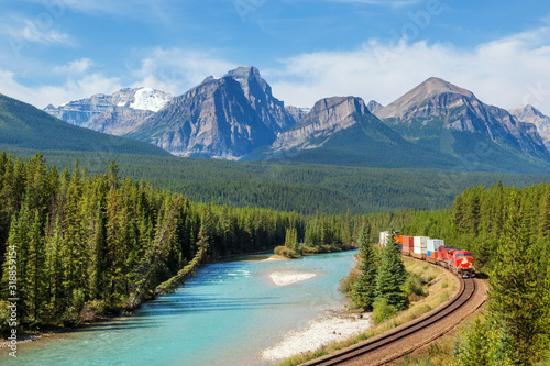 Fotomural Freight train moving along Bow river in Rocky Mountains range, Canada