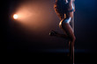 cropped view of seductive stripper in underwear dancing striptease near pylon on blue with orange lighting