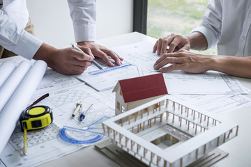 Wall Mural - Construction engineering or architect discussing a blueprint and building model while checking information on sketching meeting for architectural project in work site