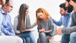 Support group members comforting depressed woman at psychotherapy session