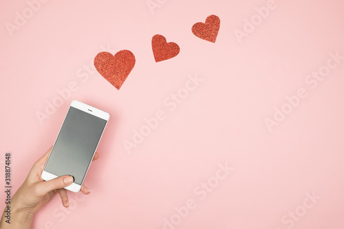 Fotografía Valentine's day concept, mobile phone screen with red hearts on pink background