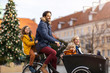 © pikselstock - Young family riding in a cargo bicycle during Christmas