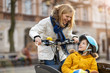 © pikselstock - Young woman and her son riding the bicycle in a city