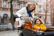 © pikselstock - Mother checking on her children who is riding in the front section of a cargo bike