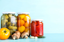 Glass Jars With Different Pickled Vegetables On Light Blue Wooden Table. Space For Text