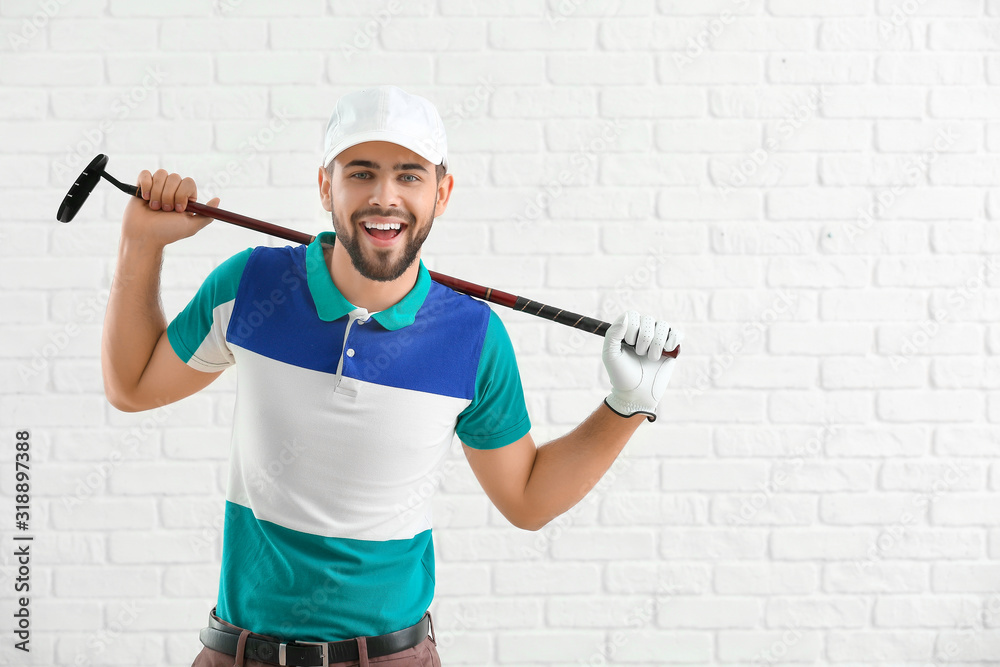Handsome male golfer on white brick background