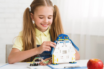 Poster - Modern technologies. Happy schoolgirl constructing robot, copy space