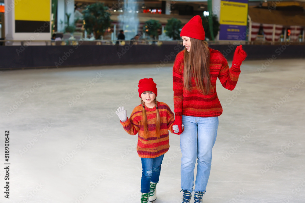 Young mother with little daughter on skating rink