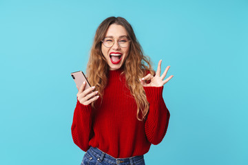 Sticker - Image of joyful woman holding cellphone and gesturing ok sign