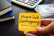 Realtor holds home sale contingency memo sign.
