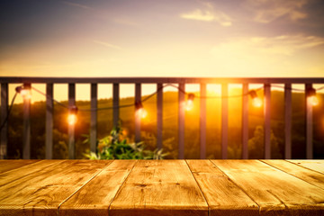 Wall Mural - Wooden board of free space for your decoration. Blurred background of balcony and ladnscape of Tuscany.Small lights and orange color of sunset time. 