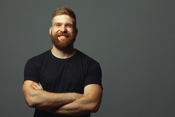 Fabulous at any age. Emotive portrait of laughing charismatic muscular 30-year-old man standing over light gray background. Perfect haircut. Rocker, biker, hipster style. Copy-space. Studio shot