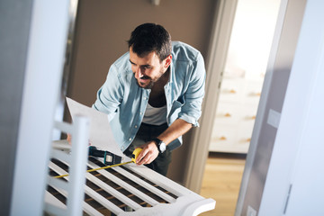 Wall Mural - Man reading instructions for assembling baby crib.