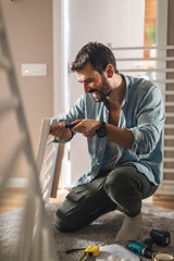 Wall Mural - Man screwing a side of a baby crib.