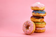 Sweet donuts stacked in a stack on a pink background. Copy space, game of color, sweet life.
