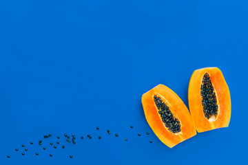 Fresh ripe orange papaya, two halves of exotic tropical fruit cut in half on blue background. Top view, copy space, place for text. Vegan or vegetarian healthy food concept.