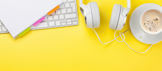 Wall Mural - Office yellow backdrop with coffee, headphones and computer