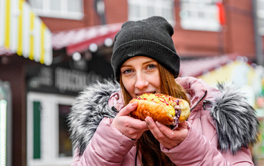 Young Woman Eating Hot dog. Street food outdoor winter