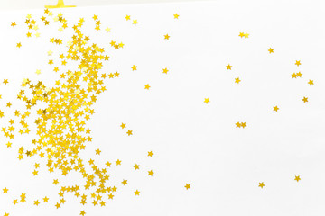 Gold confetti and stars and sparkles on a light background. Top view, flat lay. Copy text. Bright and festive background. For Christmas, New Year, Mother's Day.