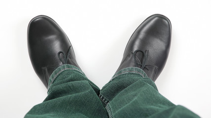 Wall Mural - Men's legs in jeans and black classic shoes on white background