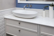 Bathroom interior in a blue pastel colors and a close up of a bathroom furniture. A bowl-shaped sink on a ultra thin quartzite countertop. Contemporary bathroom design. 