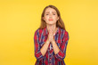Please, I'm begging! Portrait of desperate ginger girl in shirt keeping arms in prayer gesture and asking forgiveness, feeling sorry for mistake. indoor studio shot isolated on yellow background