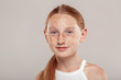 Inclusive Beauty. Girl with freckles and ponytail standing isolated on grey smiling happy close-up